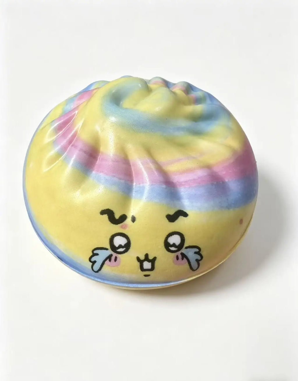 Pastel rainbow dumpling squishy toy with ribbed top, cute face and blush cheeks.