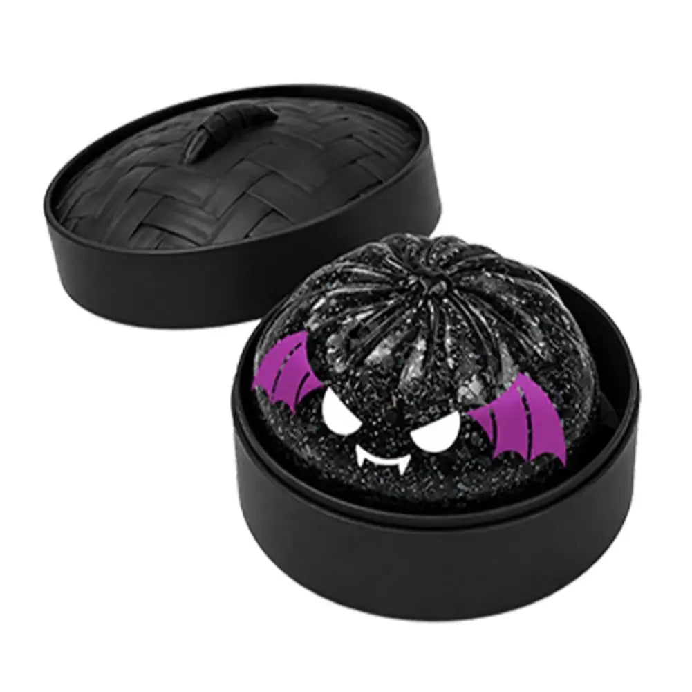 Black glitter squishy bun stress ball in black round case, spooky bat-like purple eyes