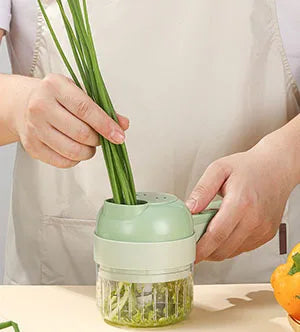 Green vegetable cutter with hands feeding long herbs into the bowl