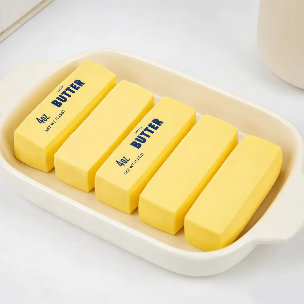 Yellow butter stick fidget toys on a white tray, rectangular salted butter bars