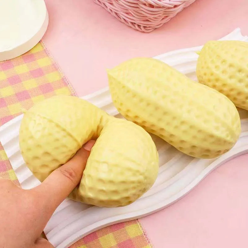 Yellow peanut-shaped squishy stress toy with bumpy surface, hand squeezing