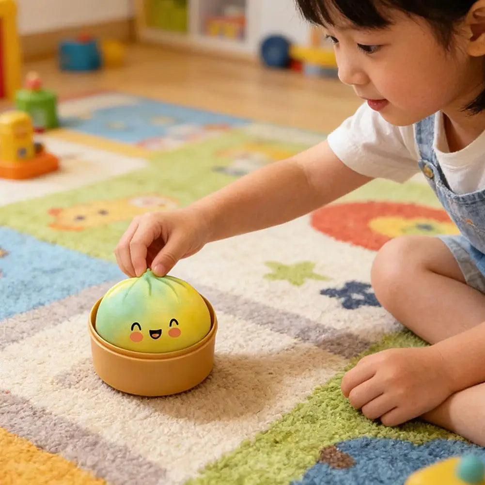 Yellow-green bun squishy stress ball with cute face, placed on play mat by child