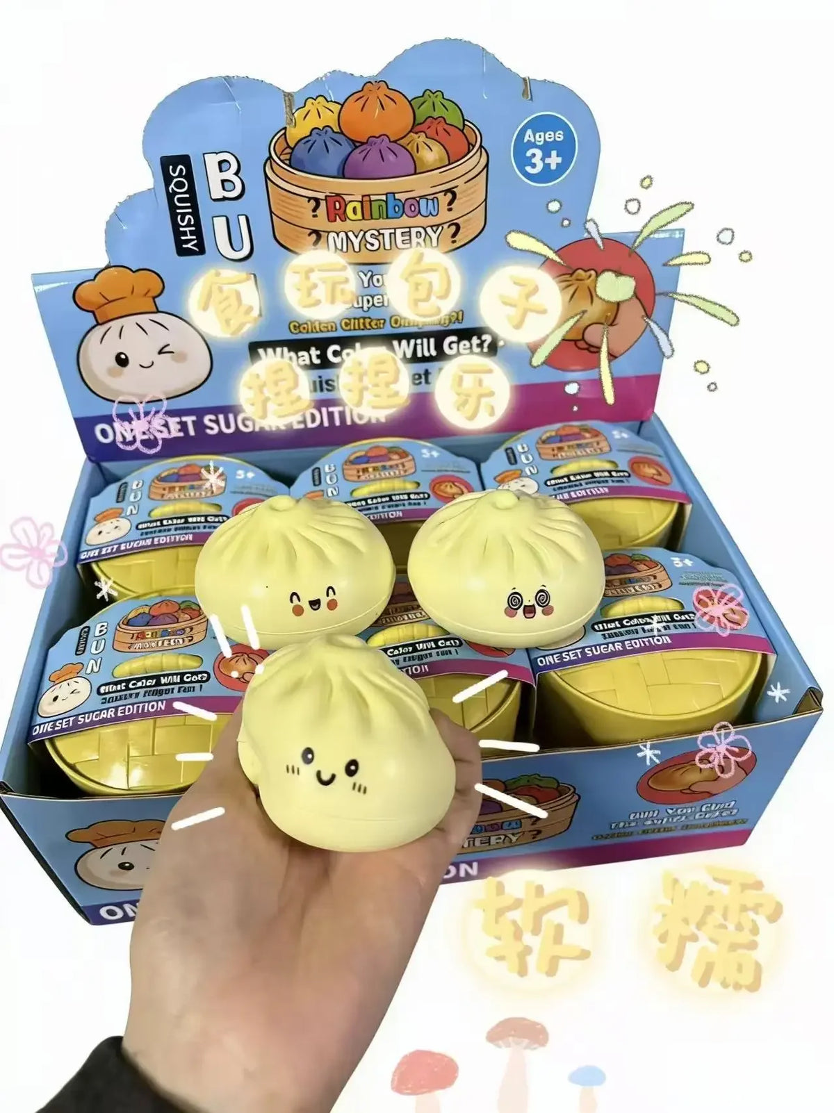 Carton display of dumpling squishy toys, with a hand holding a pale yellow one