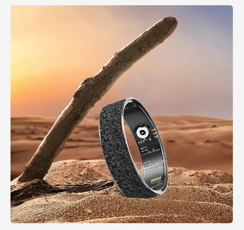 Black and silver textured health tracker ring with green LED lights, standing on sand