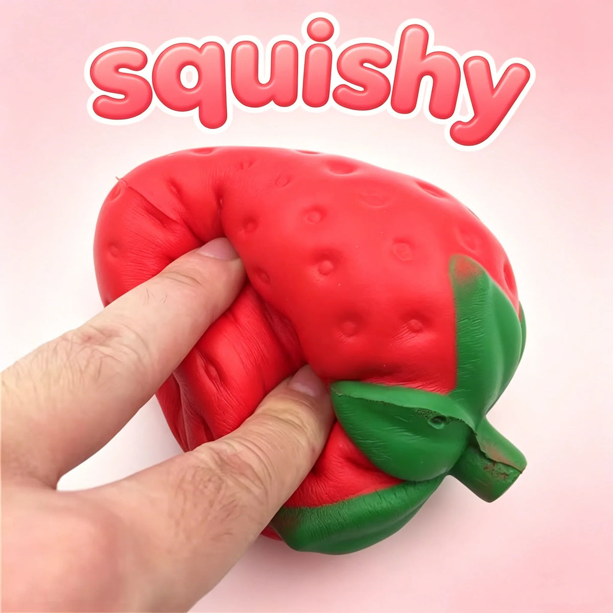 Red strawberry squishy stress ball squeezed in hands with green leafy cap; bumpy texture