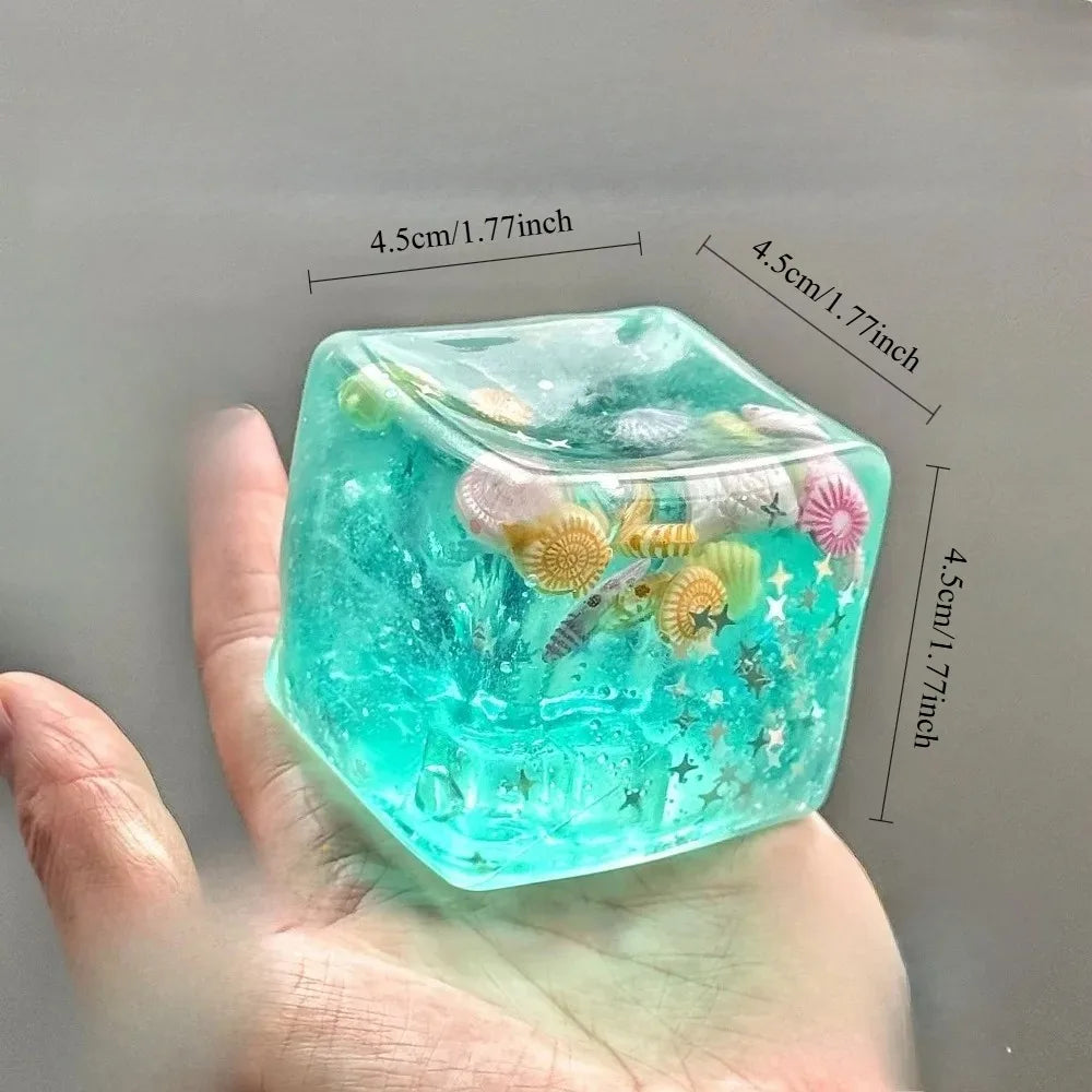 4.5 cm turquoise ocean squishy stress ball cube with sea creatures inside, held in hand