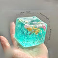 4.5 cm turquoise ocean squishy stress ball cube with sea creatures inside, held in hand