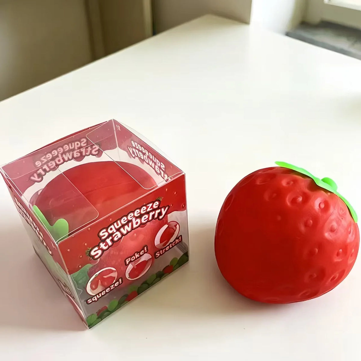 Red strawberry-shaped slow-rising squishy stress ball with green leafy top