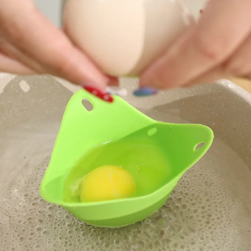 Green silicone egg poacher cup on countertop with a cracked egg inside