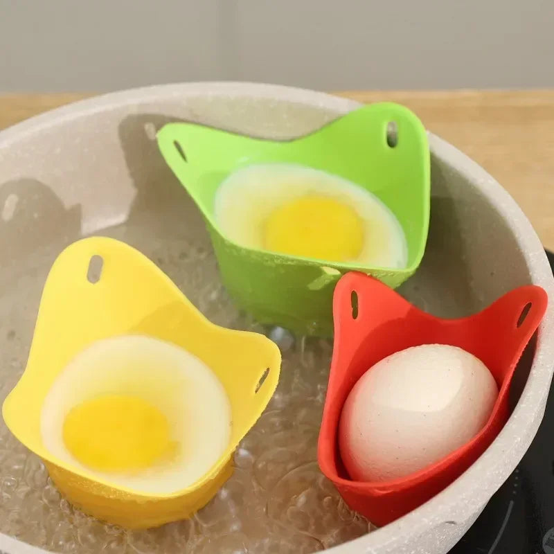 Colorful silicone egg poacher cups (red, green, yellow) holding eggs in a tray.