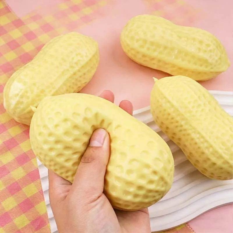 Yellow peanut-shaped squishy stress toy with bumpy texture, several toys nearby