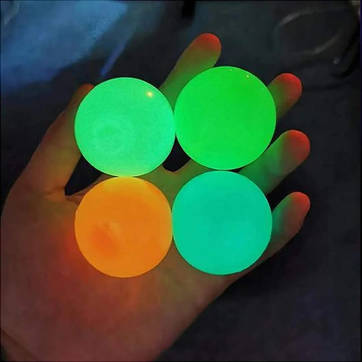 Glow sticky balls in a hand: green, orange, and red-orange clustered together