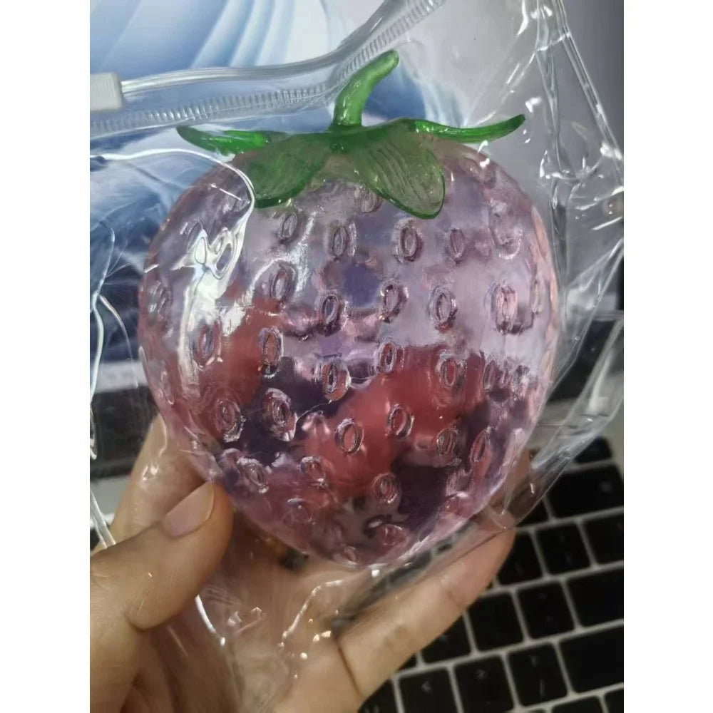 Red strawberry squishy stress ball inside clear packaging with green leaf top
