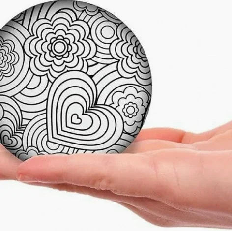 White stress ball with black swirl and flower doodle design, gripped by hand
