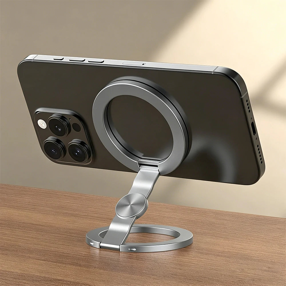Silver magnetic phone ring holder with pivot joint and round base on tabletop