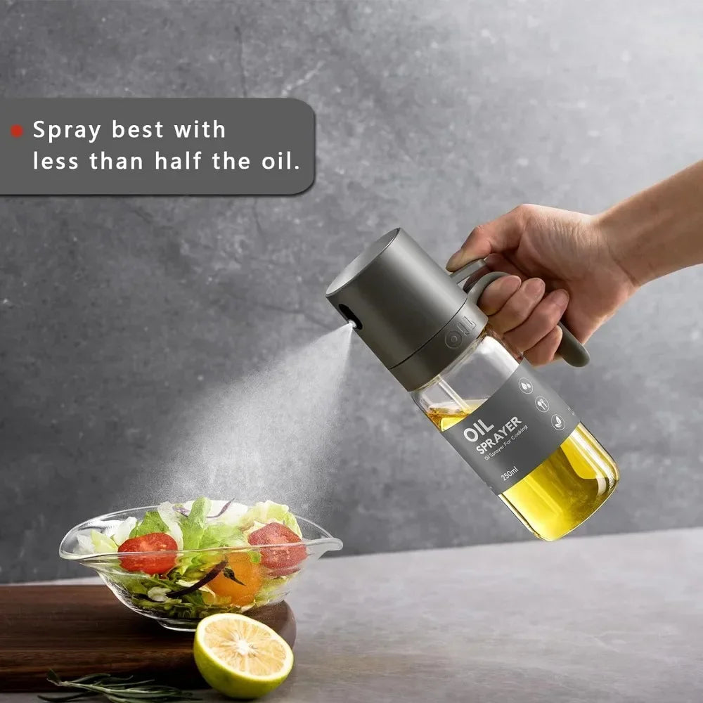 Hand holding glass oil sprayer bottle with matte gray top for a fine cooking oil mist