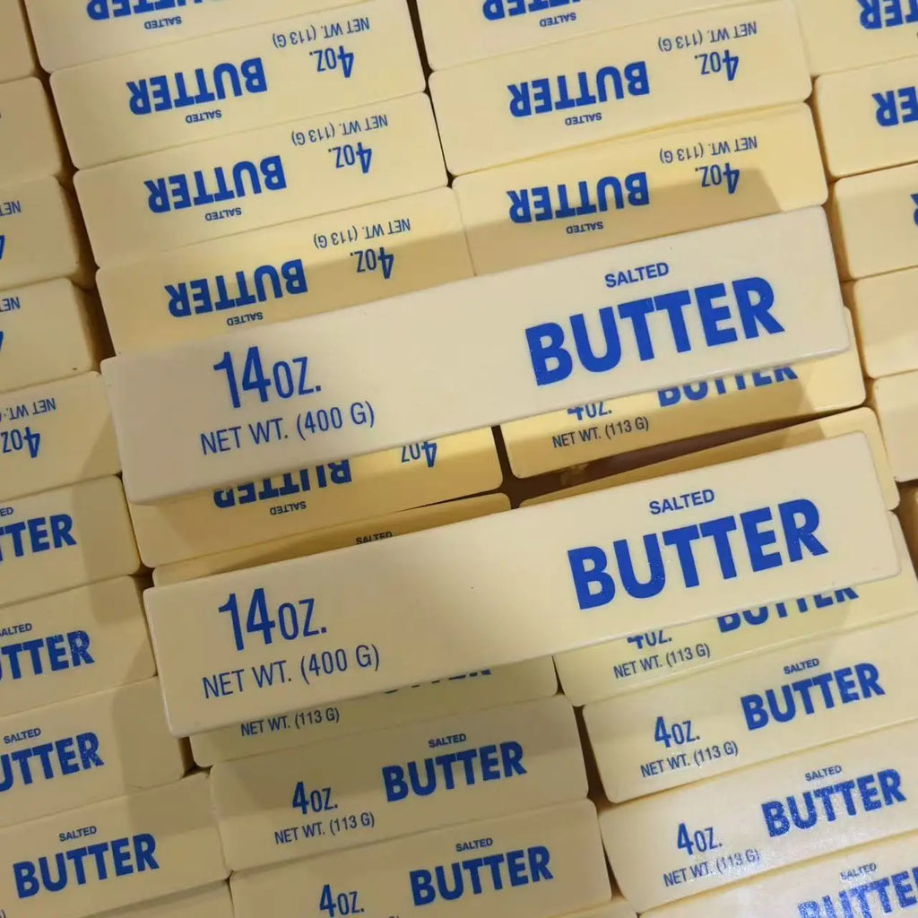 Stack of yellow butter stick fidget toys with blue “BUTTER” labels and 4oz text