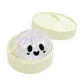 Glittery white squishy bun stress ball in pale green round storage case, smiling face