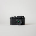Black compact digital camera with textured grip and attached lens