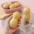 Pale yellow peanut squishy stress toys in a basket; one held in hand